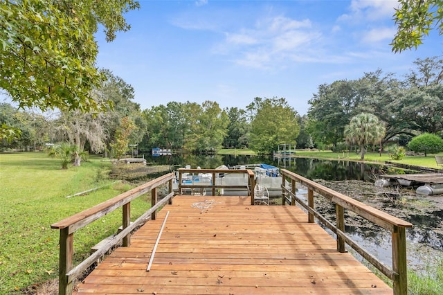 view of dock with a yard and a water view