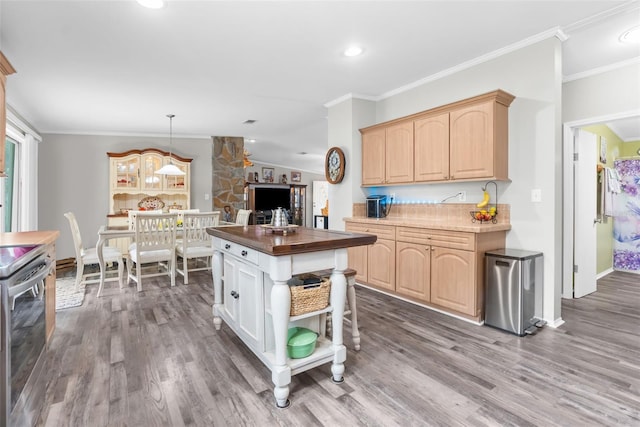 kitchen with crown molding, light brown cabinetry, a kitchen island, and stove