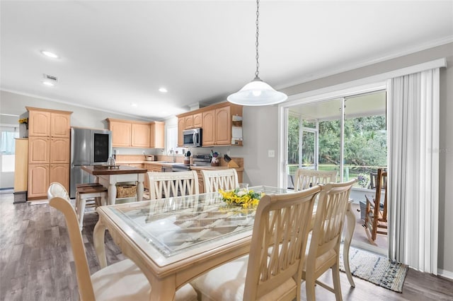 dining area featuring crown molding, sink, and light wood-type flooring