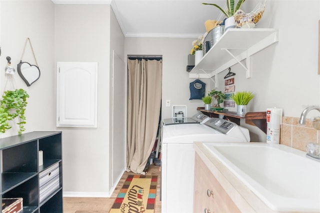 washroom featuring crown molding, sink, independent washer and dryer, and light hardwood / wood-style floors