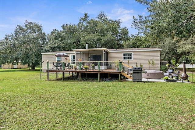 back of property featuring a yard, a hot tub, a sunroom, and a deck