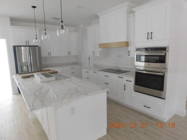 kitchen with pendant lighting, a center island, white cabinets, and stainless steel appliances