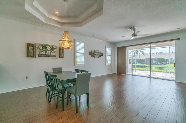 dining room with ceiling fan with notable chandelier, ornamental molding, dark hardwood / wood-style floors, and a raised ceiling