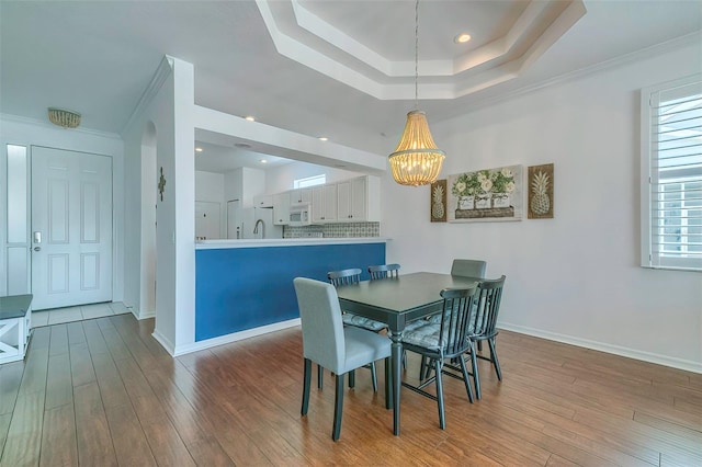 dining space featuring ornamental molding, an inviting chandelier, and light hardwood / wood-style flooring