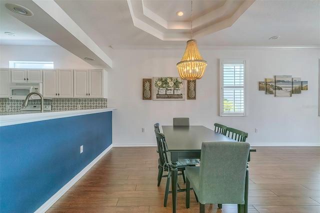 dining space featuring an inviting chandelier, a tray ceiling, dark hardwood / wood-style floors, and crown molding