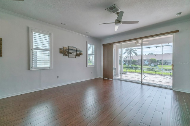 empty room with ceiling fan, ornamental molding, a textured ceiling, and dark wood-type flooring