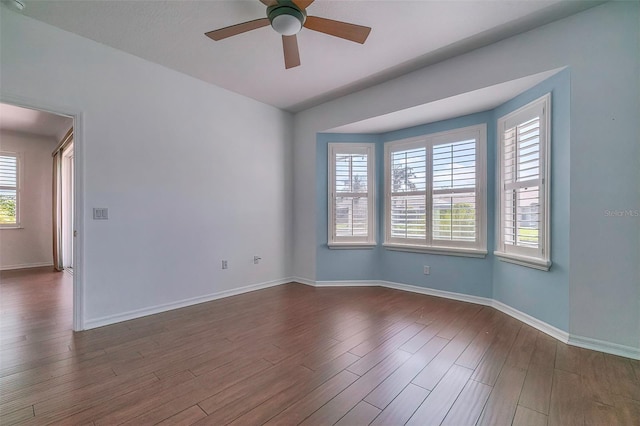 unfurnished room featuring ceiling fan, plenty of natural light, and dark wood-type flooring