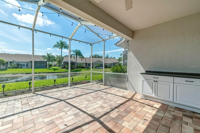 view of patio / terrace featuring glass enclosure and a water view