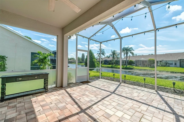 unfurnished sunroom featuring ceiling fan and a water view