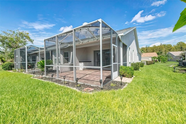 back of property featuring a yard, glass enclosure, and a patio