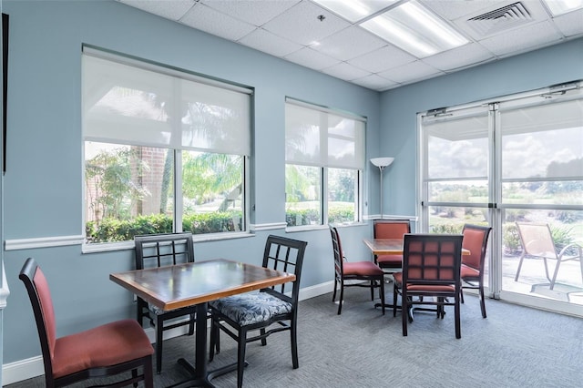 carpeted dining room with a healthy amount of sunlight and a paneled ceiling