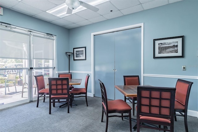 carpeted dining area featuring ceiling fan and a drop ceiling