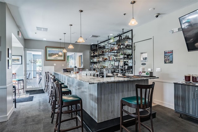 bar featuring dark carpet, light stone countertops, and pendant lighting