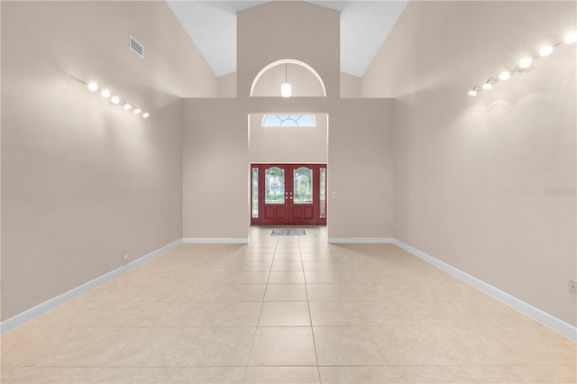 tiled spare room featuring high vaulted ceiling