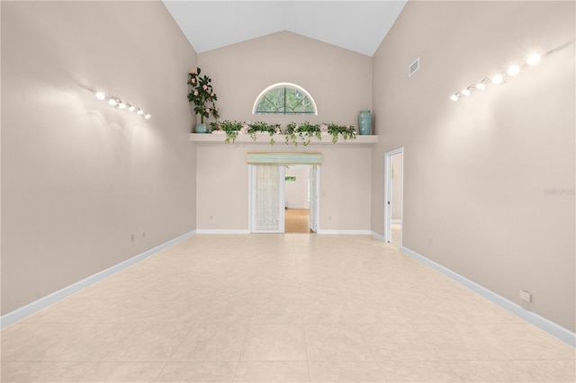 empty room featuring high vaulted ceiling and light tile patterned flooring