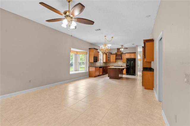 kitchen featuring black fridge, pendant lighting, a center island, ceiling fan with notable chandelier, and decorative backsplash