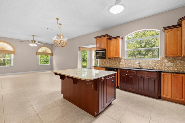 kitchen featuring a wealth of natural light, stainless steel microwave, and hanging light fixtures