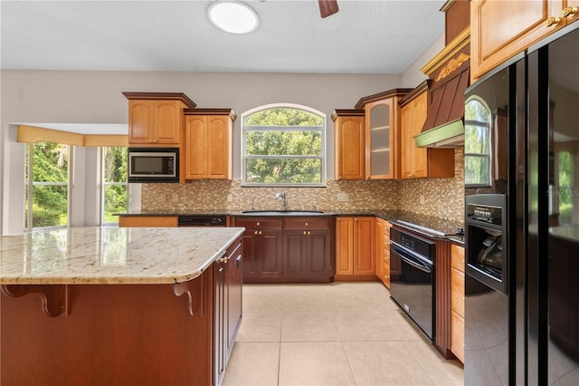 kitchen with light stone countertops, black appliances, sink, and tasteful backsplash