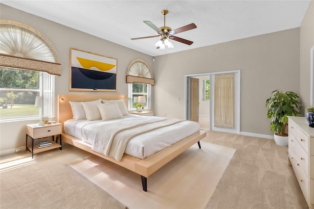 bedroom with ceiling fan, light colored carpet, and a textured ceiling