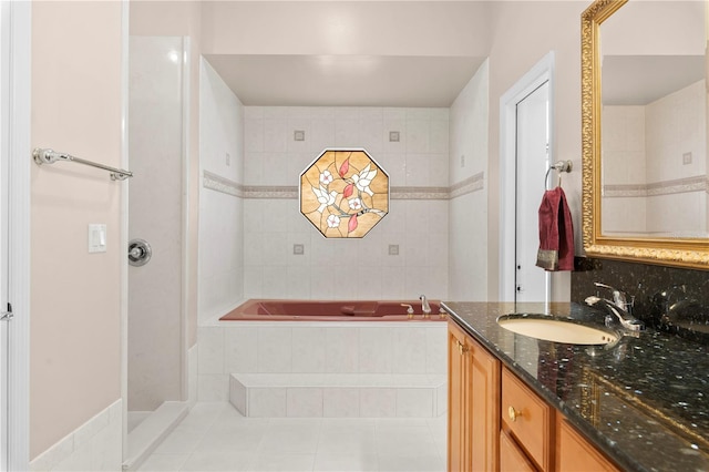 bathroom with tiled bath, vanity, and tile patterned flooring