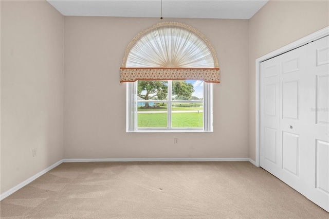 unfurnished bedroom with light carpet and a closet