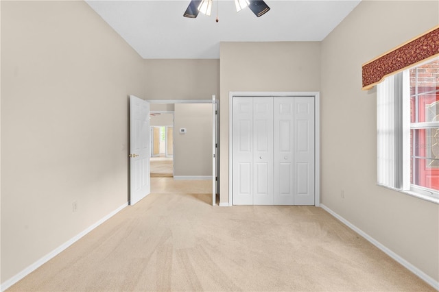 unfurnished bedroom with light carpet, a closet, and ceiling fan