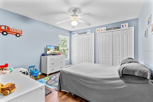 bedroom with multiple closets, ceiling fan, a textured ceiling, and wood finished floors