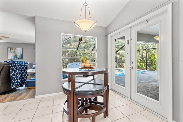 dining room featuring lofted ceiling, french doors, light tile patterned flooring, and baseboards