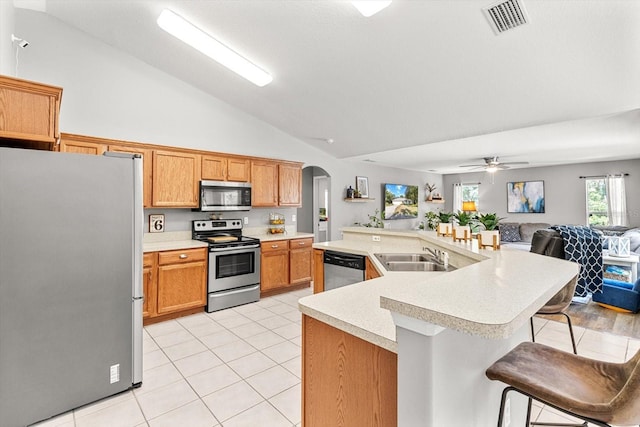 kitchen with arched walkways, appliances with stainless steel finishes, open floor plan, light countertops, and a sink