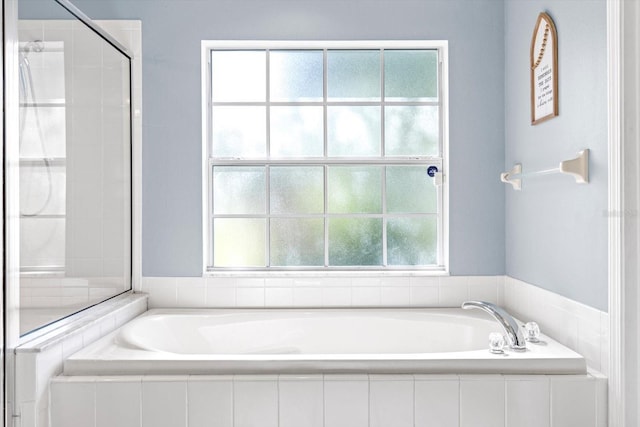 bathroom featuring a shower stall and a bath