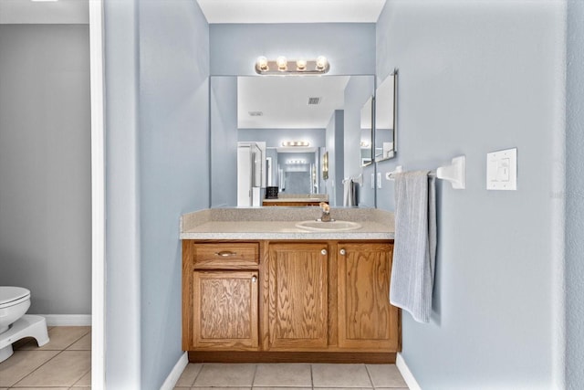 bathroom featuring vanity, tile patterned flooring, toilet, and baseboards