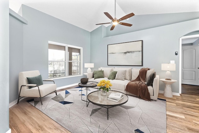 living room featuring arched walkways, a ceiling fan, wood finished floors, high vaulted ceiling, and baseboards