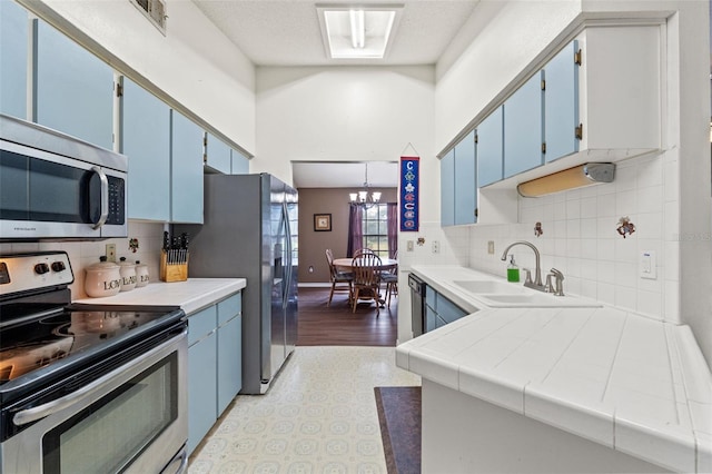 kitchen with stainless steel appliances, light hardwood / wood-style floors, tile counters, and blue cabinetry