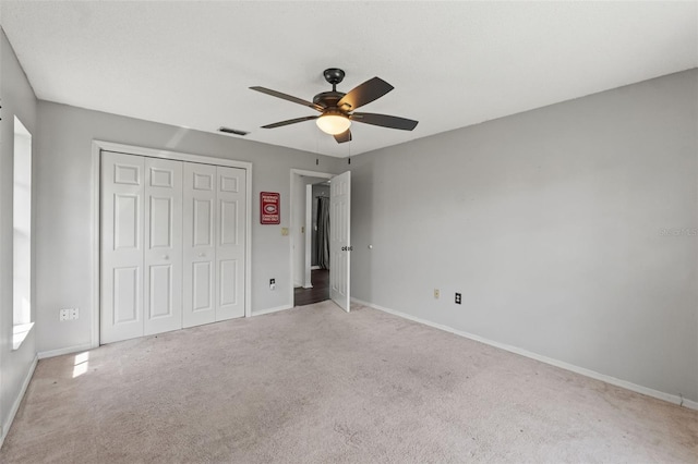 unfurnished bedroom featuring a closet, ceiling fan, and light colored carpet