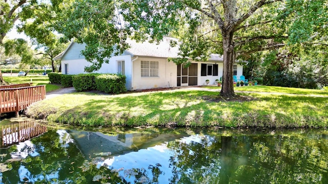 back of property with a lawn and a water view