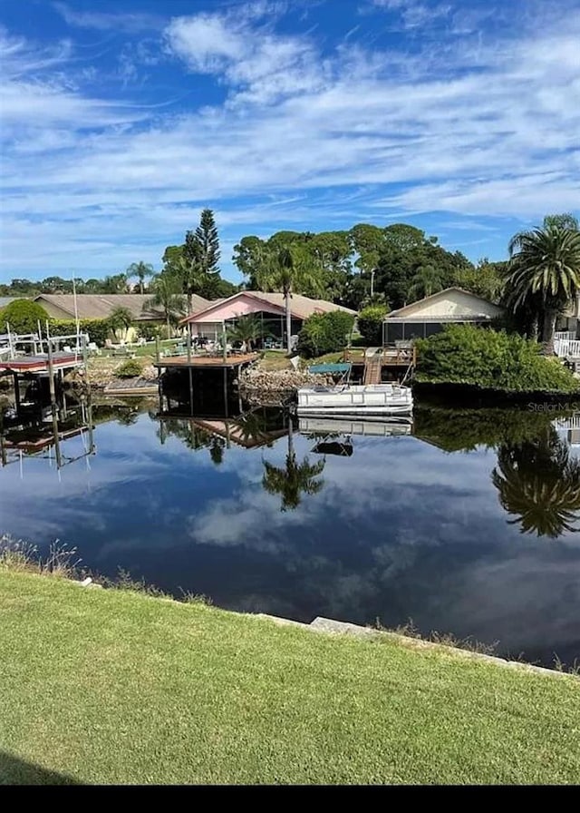 view of dock with a lawn and a water view