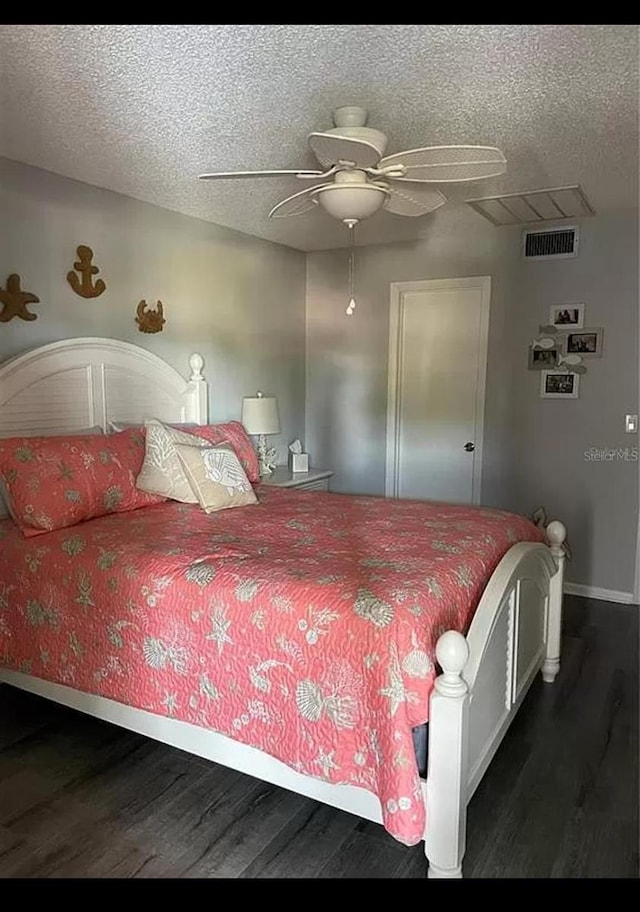 bedroom with ceiling fan, a textured ceiling, and dark hardwood / wood-style floors