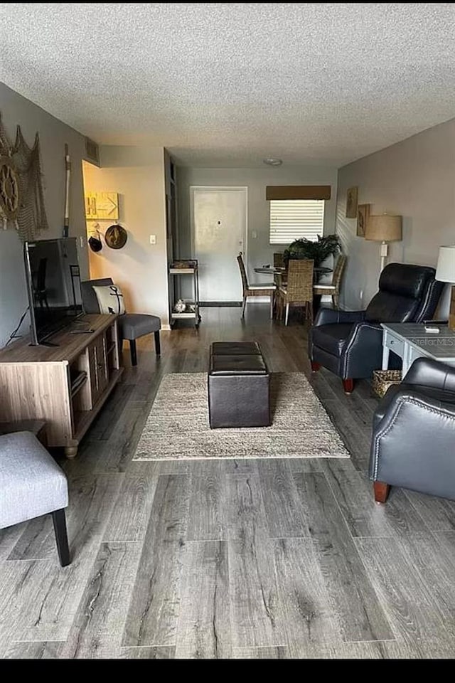 living room featuring a textured ceiling and dark hardwood / wood-style floors