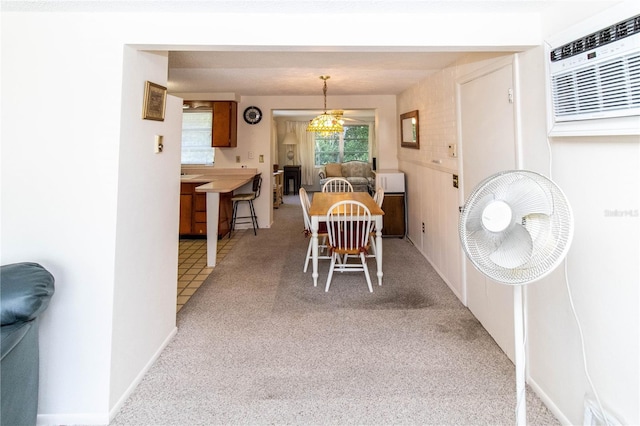 dining space with an AC wall unit, light colored carpet, and a notable chandelier