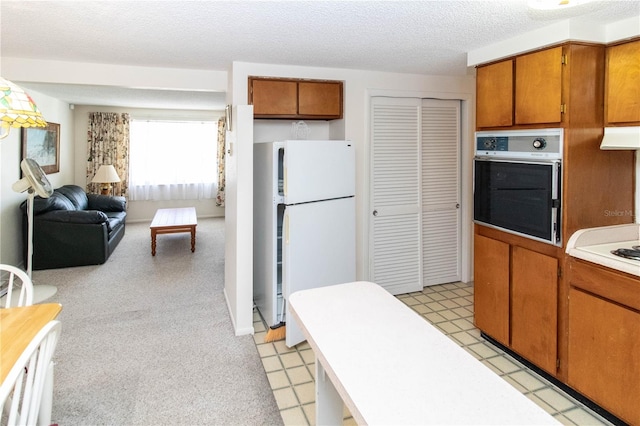 kitchen featuring white refrigerator, a textured ceiling, ventilation hood, light colored carpet, and oven