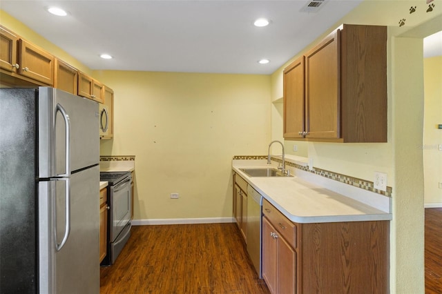 kitchen with appliances with stainless steel finishes, dark hardwood / wood-style floors, and sink