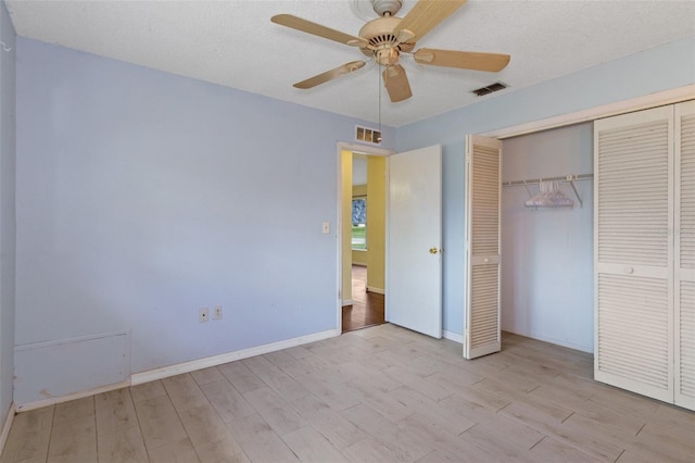 unfurnished bedroom featuring a closet, light wood-type flooring, ceiling fan, and a textured ceiling