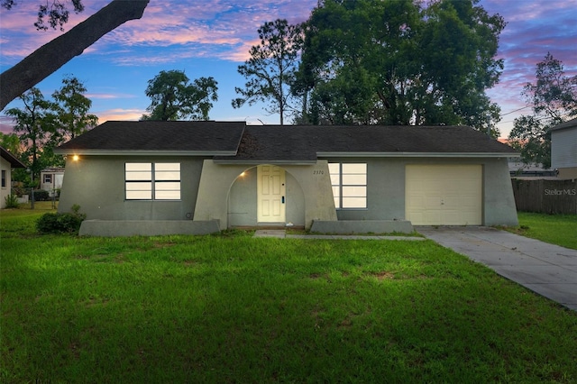 ranch-style home with a garage and a yard