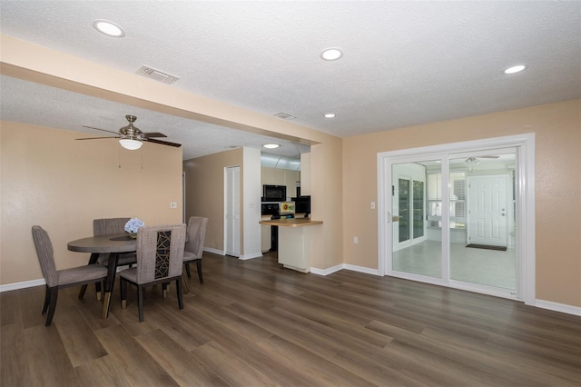 dining area with a textured ceiling, ceiling fan, and dark wood-type flooring