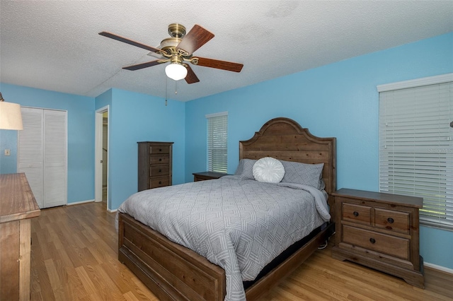 bedroom featuring light hardwood / wood-style flooring, a closet, ceiling fan, and a textured ceiling