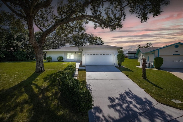 ranch-style house with a garage and a lawn