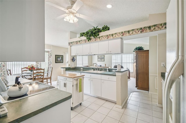 kitchen featuring white cabinets, kitchen peninsula, a textured ceiling, and sink