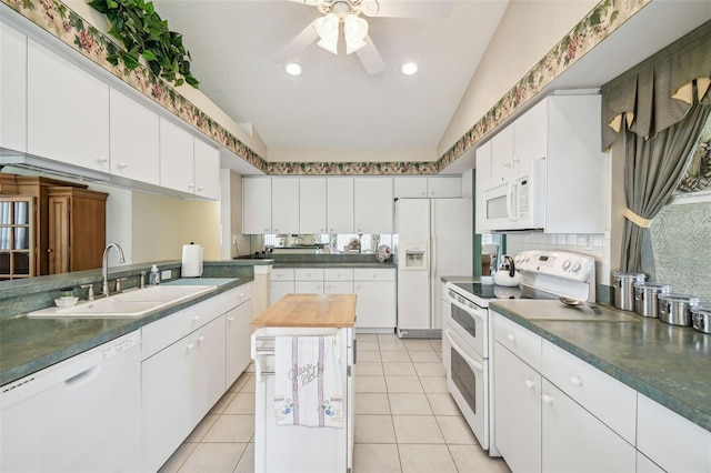 kitchen with white appliances, white cabinetry, sink, and vaulted ceiling