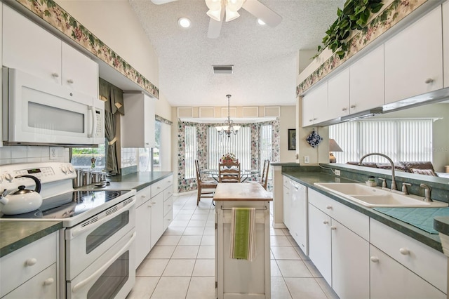 kitchen featuring white cabinetry, sink, a textured ceiling, white appliances, and lofted ceiling