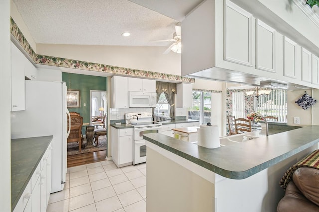 kitchen with white cabinetry, kitchen peninsula, white appliances, and vaulted ceiling